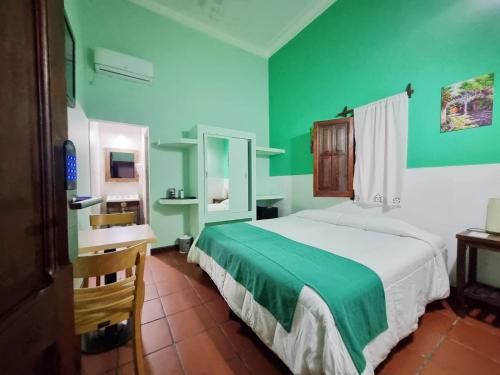 萨尔塔雷富希奥德尔印加酒店的一间卧室配有一张床和一张书桌,拥有绿色的墙壁