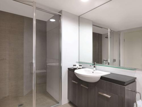 悉尼悉尼机场阿迪纳公寓式酒店的一间带水槽和玻璃淋浴的浴室