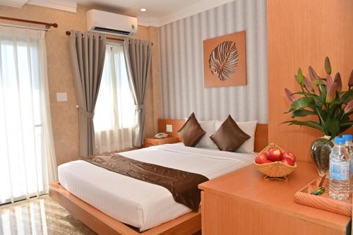 巴地市Trân Châu Beach & Resort的一间卧室配有一张床和一张带水果的桌子