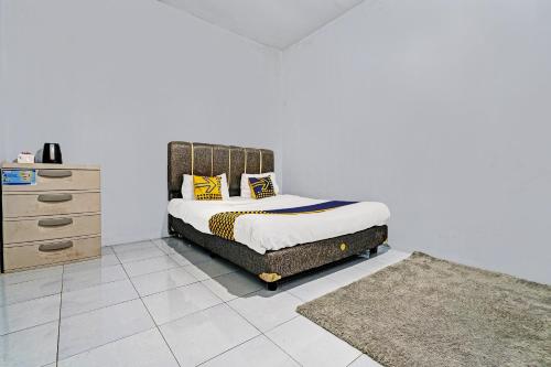 伦邦OYO 92269 Arjuna Homestay的一间卧室配有一张带黄色枕头的床和梳妆台