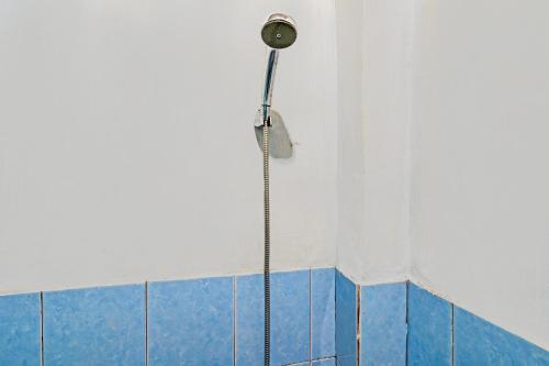 伦邦OYO 92269 Arjuna Homestay的浴室铺有蓝色和白色瓷砖,设有淋浴。