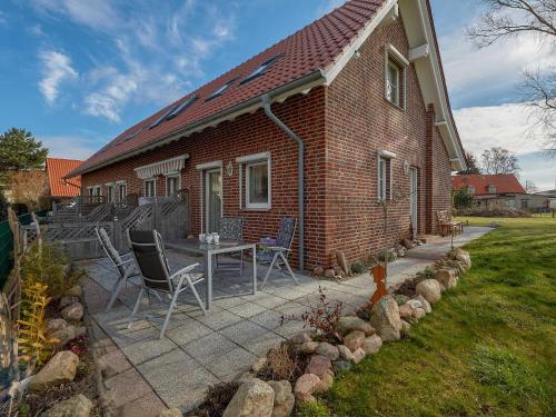 洛布Ferienhaus Lobbe - Wohnung 01 mit Terrasse strandnah的砖屋,设有配有椅子和桌子的庭院