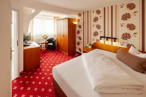 莱比锡柏林酒店的一间酒店客房,配有一张白色的床和一张书桌