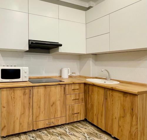 阿拉木图Modern Studio with Panoramic Mountain View的一间带木制橱柜和微波炉的厨房