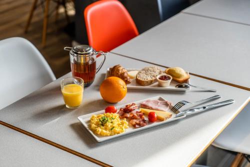 奥尔良ibis Orléans Centre Foch的一张桌子,上面放着一盘早餐食品和橙汁