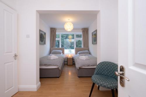 伯恩茅斯Modern apt near gardens with large decking area - Vivre Retreats的客房设有两张床、一把椅子和窗户。