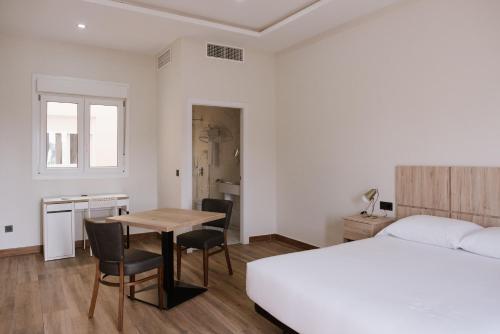 梅利利亚Melilla Centro Hotel ***的卧室配有一张床和一张桌子及椅子
