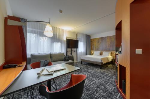 慕尼黑慕尼黑帕克斯塔特斯瓦宾诺富特套房酒店的酒店客房配有沙发和桌椅