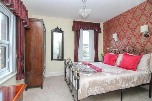 滨海韦斯顿The Beach House Luxury Rooms Weston Super Mare的一间卧室配有一张带红色枕头的大床