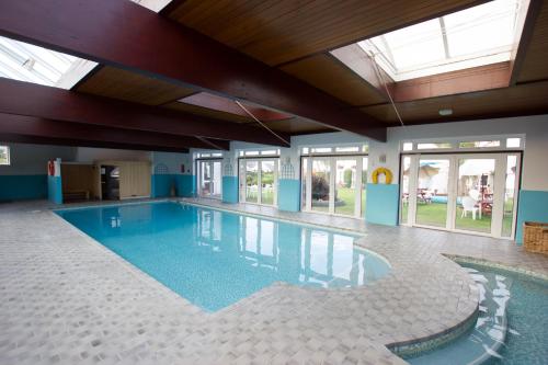 Grouville伯希特酒店 的一座大型游泳池,位于一座带窗户的建筑内