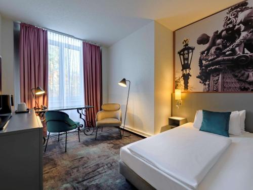 汉诺威美居汉诺威城市酒店的酒店客房,配有一张床、一张桌子和椅子