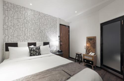 基隆香草艺术旅店的卧室配有一张白色大床和一堵墙