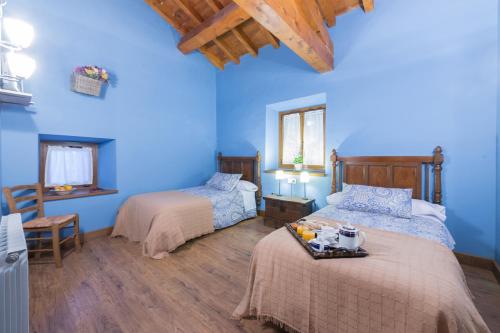 Esnoz艾克兰达乡村民宿的一间卧室设有两张床,拥有蓝色的墙壁。