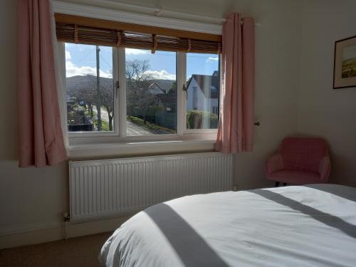 Ben RhyddingGrange Croft的一间卧室设有一张床和一个带红色椅子的窗户