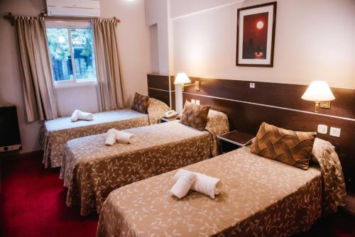 门多萨Hotel Pacífico的酒店客房设有三张床和窗户。
