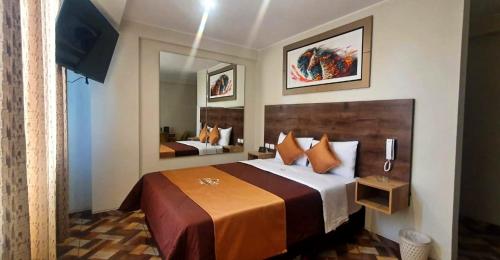 利马Hotel Cesar´s的酒店客房配有一张带橙色枕头的大床