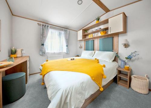 PerranzabuloePerran Heights Holiday Park的一间卧室配有一张带黄色毯子的大床