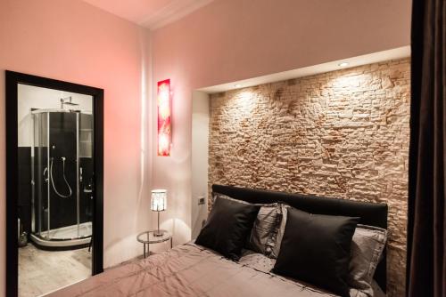 罗马特雷维万神殿奢华客房住宿加早餐旅馆的一间卧室设有砖墙和一张带镜子的床