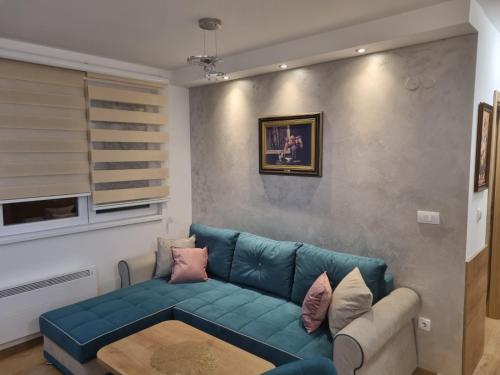 亚霍里纳Vila Jahor Apartman Miro的客厅配有蓝色的沙发和桌子