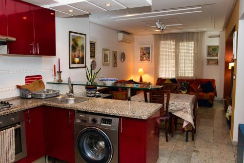 苏塞DESiGN UNQUE appartement的一间带红色橱柜的厨房和一间客厅