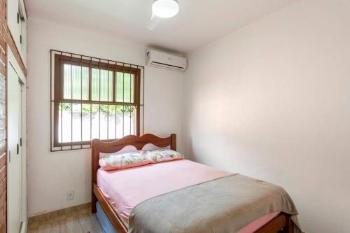 萨夸雷马CASA CORAL SAQUAREMA的一间卧室配有一张带粉色床单的床和一扇窗户。