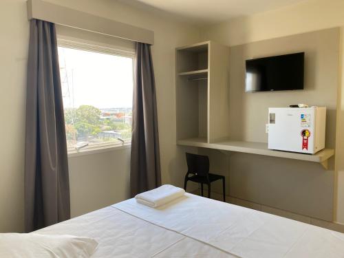 乌贝兰迪亚San Martin Hotel的一间卧室设有一张床和一个带冰箱的窗户