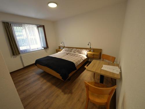 Le Paquier伯恩奥伯格布奈酒店的一间卧室配有一张床和一张木桌及桌子