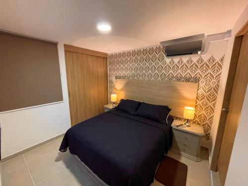 卡利Apartamento en Cali Inn tropical CLO的一间卧室配有一张大床和一个带灯的床头柜