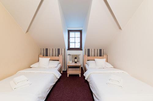 赫拉德茨 - 克拉洛韦诺维阿达波提姆酒店的阁楼间配有2张床和白色床单
