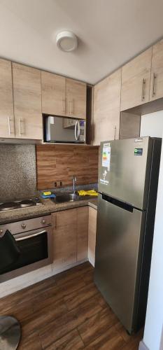 伊基克Departamento Iquique Nuevo Centro的厨房配有不锈钢冰箱和木制橱柜