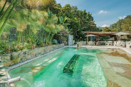 马尼萨莱斯Hotel Termales Tierra Viva的后院设有带桌椅的无边泳池
