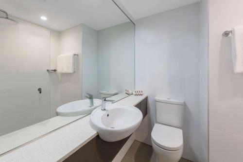 悉尼悉尼机场旅客之家酒店的白色的浴室设有水槽和卫生间。