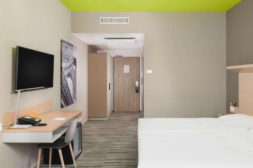 布达佩斯布达佩斯丽笙布鲁酒店的酒店客房配有一张床、一张书桌和一台电视。
