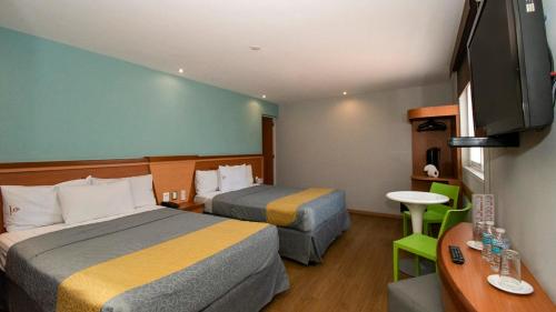 墨西哥城Hotel El Conde Naucalpan Only Adults的酒店客房设有两张床和一台平面电视。