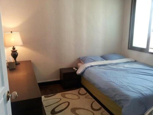 蔚山Ramnant Guest House的一间卧室配有一张床、一张桌子和一盏灯