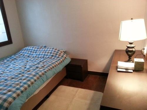 蔚山Ramnant Guest House的一间卧室配有一张床和一张带台灯的桌子