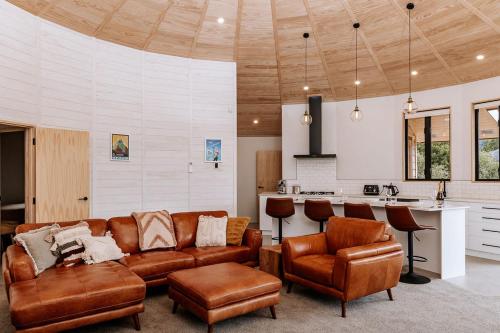 奥阿库尼Kaho - Ohakune Holiday Home with Spa的带沙发和椅子的客厅以及厨房。