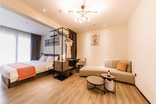 深圳京基京寓酒店(深圳龙岗大运中心店)的一间卧室配有一张床、一张沙发和一张桌子