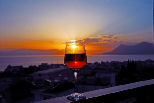 卢特拉艾季普苏Mitho Hotel Spa的坐在一个享有日落美景的山 ⁇ 上喝一杯葡萄酒