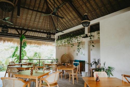 龙目岛库塔PORTER HOTEL - Surf & Yoga Retreat的餐厅设有木桌和椅子,种有植物