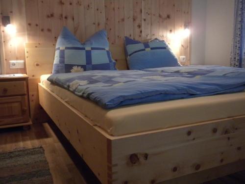 皮恩山口附近施皮塔尔丹巴赫生态休养农家乐的一间卧室配有一张带蓝色和白色枕头的床