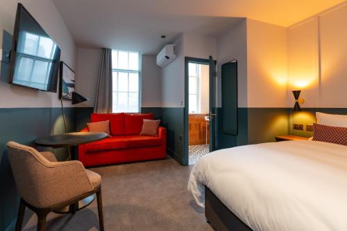 伦敦帕丁顿荣耀酒店的酒店客房,配有一张床和一张红色的沙发