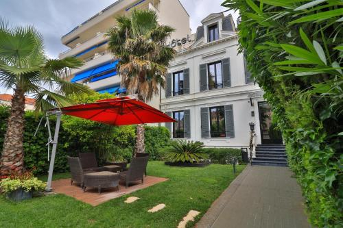 戛纳戛纳中心普鲁伊别墅酒店的房屋前带红伞的庭院