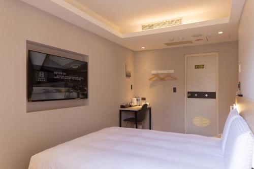 台北旅居文旅板橋驛站-湳雅夜市館Hub Hotel Banqiao inn-Nanya Night Market Branch的卧室配有白色的床和平面电视。
