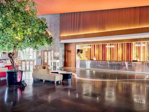 巨港巨港诺富特酒店的大楼内一个带沙发和桌子的大堂