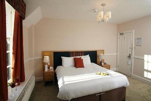 德里门Buchanan Arms Hotel & Leisure Club的一间卧室配有一张大床,配有白色床单和红色枕头