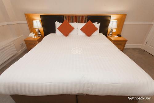 德里门Buchanan Arms Hotel & Leisure Club的卧室内一张带橙色枕头的大型白色床