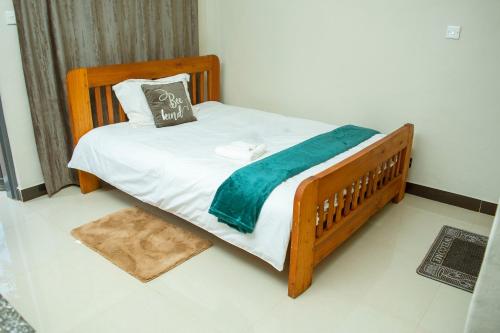 利隆圭Avon Garden Apartments Area 25的一张带蓝色毯子和枕头的木床