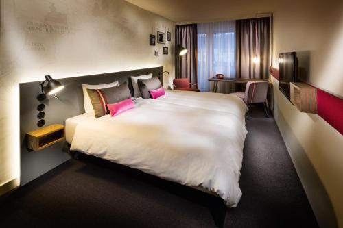 鲁瓦西昂法兰西pentahotel Paris Charles de Gaulle的酒店客房配有一张带粉红色枕头的大型白色床。