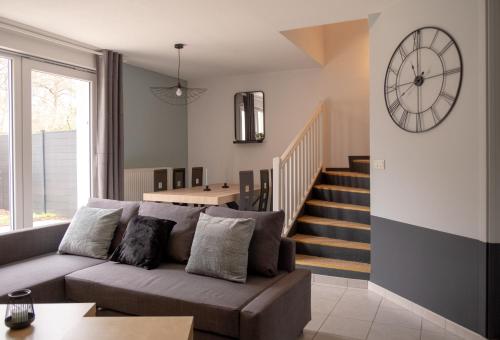 阿格诺Maison - Le Terra Verde - Terrasse的客厅配有沙发和墙上的时钟